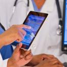 Medical workers looking a a medical record on a tablet and screen