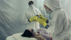 Doctors in hazmat suits treating patient.