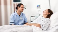 A nurse sitting beside a patient in bed
