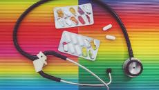 Stethoscope and pills on rainbow background